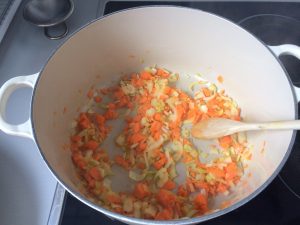 Añadimos la cebolla, el ajo, las zanahorias y el apio a la cacerola y sofreímos hasta que la cebolla esté pochada y las verduras un poco blandas