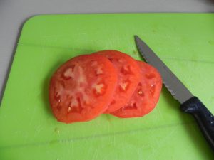 Cortamos un tomate rojo maduro en rodajas